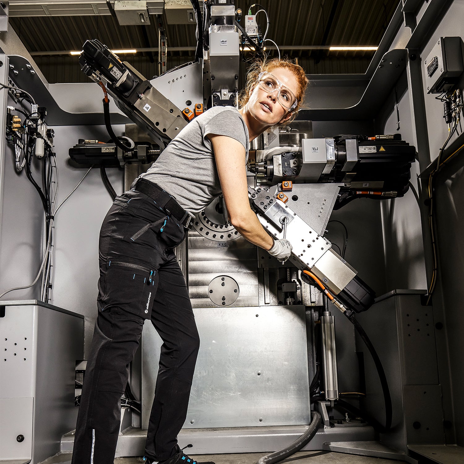 Frau in Arbeistkleidung von Albatros bedient eine große Industriemaschine.