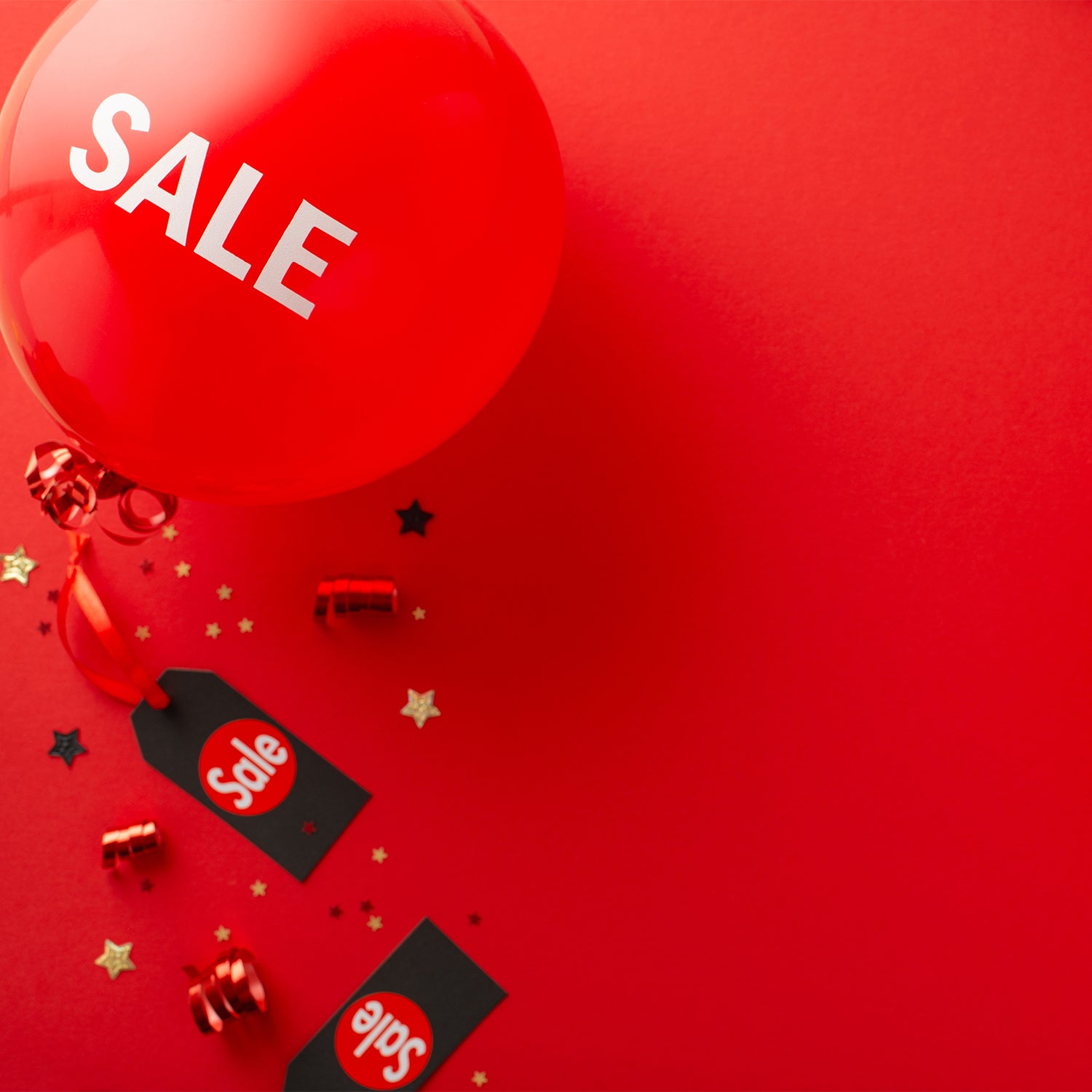Roter Hintergrund mit großem Ballon mit „SALE“ Schriftzug, umgeben von Konfetti, Geschenkbändern und schwarzen Anhängern mit „Sale“-Aufdruck
