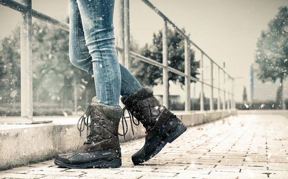 Winterstiefel von Albatros im Einsatz – Person mit Jeans steht auf einem verschneiten Gehweg, Schneefall im Hintergrund.