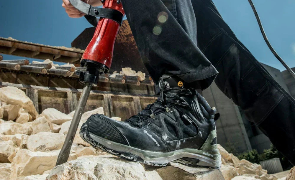 Arbeiter mit Presslufthammer auf Baustelle, trägt den robusten Sicherheitsschuh ‚Ultratrail CTX‘ von Albatros auf hellem Gestein – Fokus auf Schuhprofil und dynamischem Einsatzumfeld.