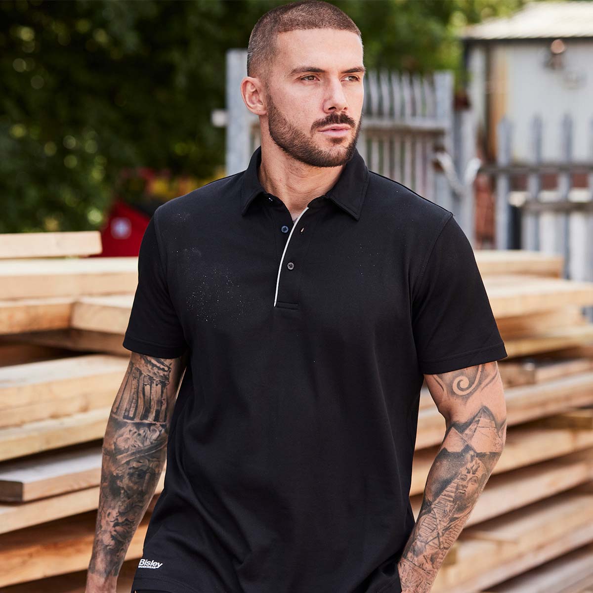 Handwerker in schwarzem Bisley Workwear Poloshirt mit kurzen Ärmeln – moderne und strapazierfähige Arbeitskleidung für Baustelle und Handwerk.