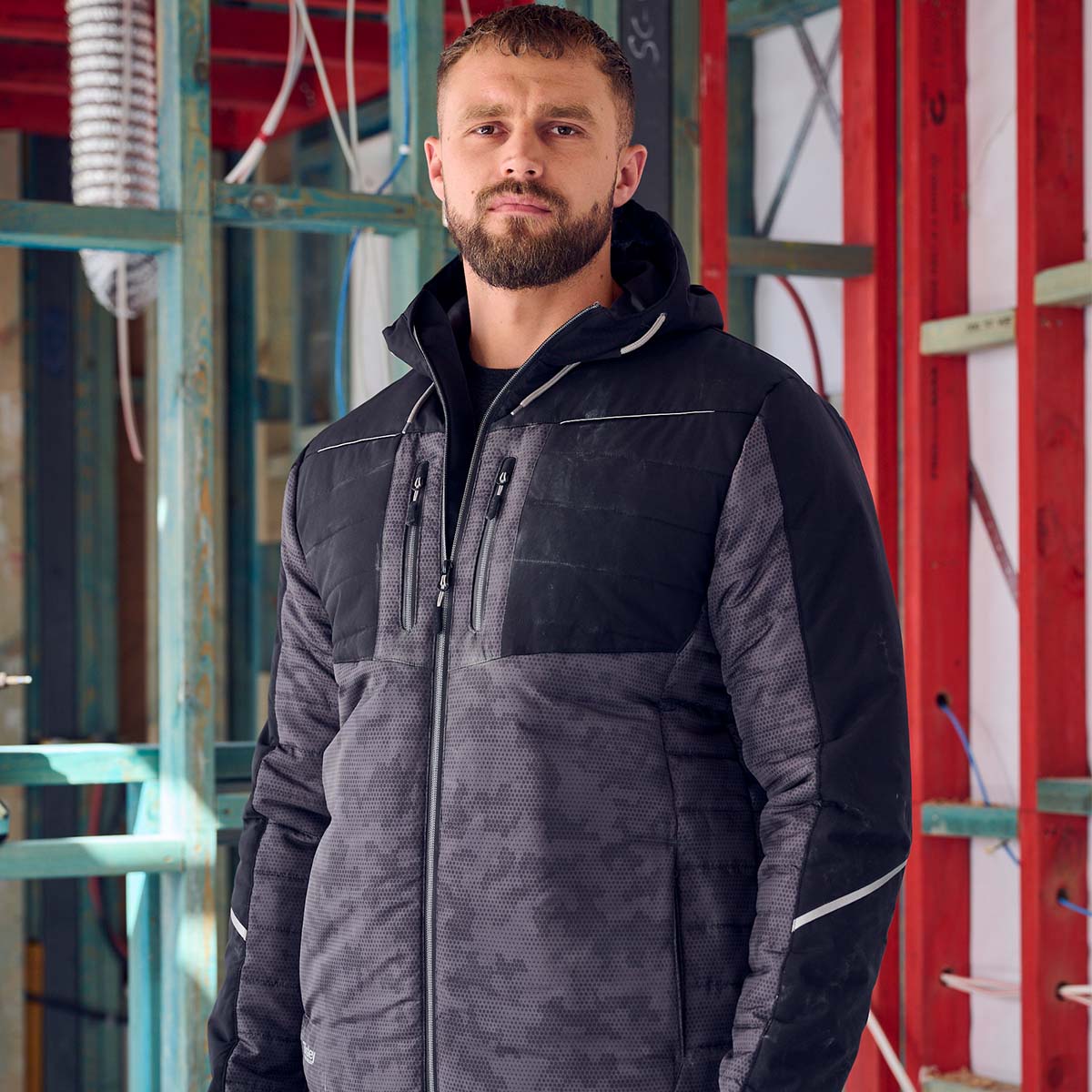 Handwerker trägt schwarze Bisley Arbeitsjacke mit Kapuze – robuste, wetterfeste Workwear für Baustelle und Handwerk.