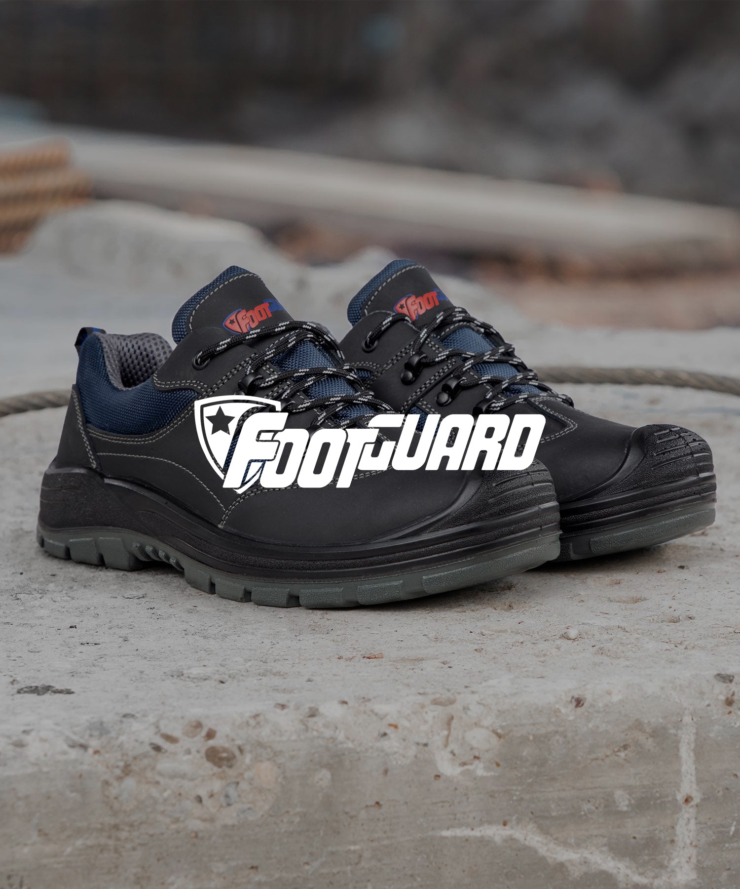 Sicherheitsschuh "Safe" von Footguard in Schwarz mit blauem Mesh-Einsätzen, stehend auf hellem Betonboden.