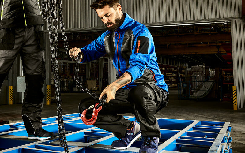 Handwerker bei Kranmontage in moderner Arbeitskleidung von Albatros in einer Industriehalle.