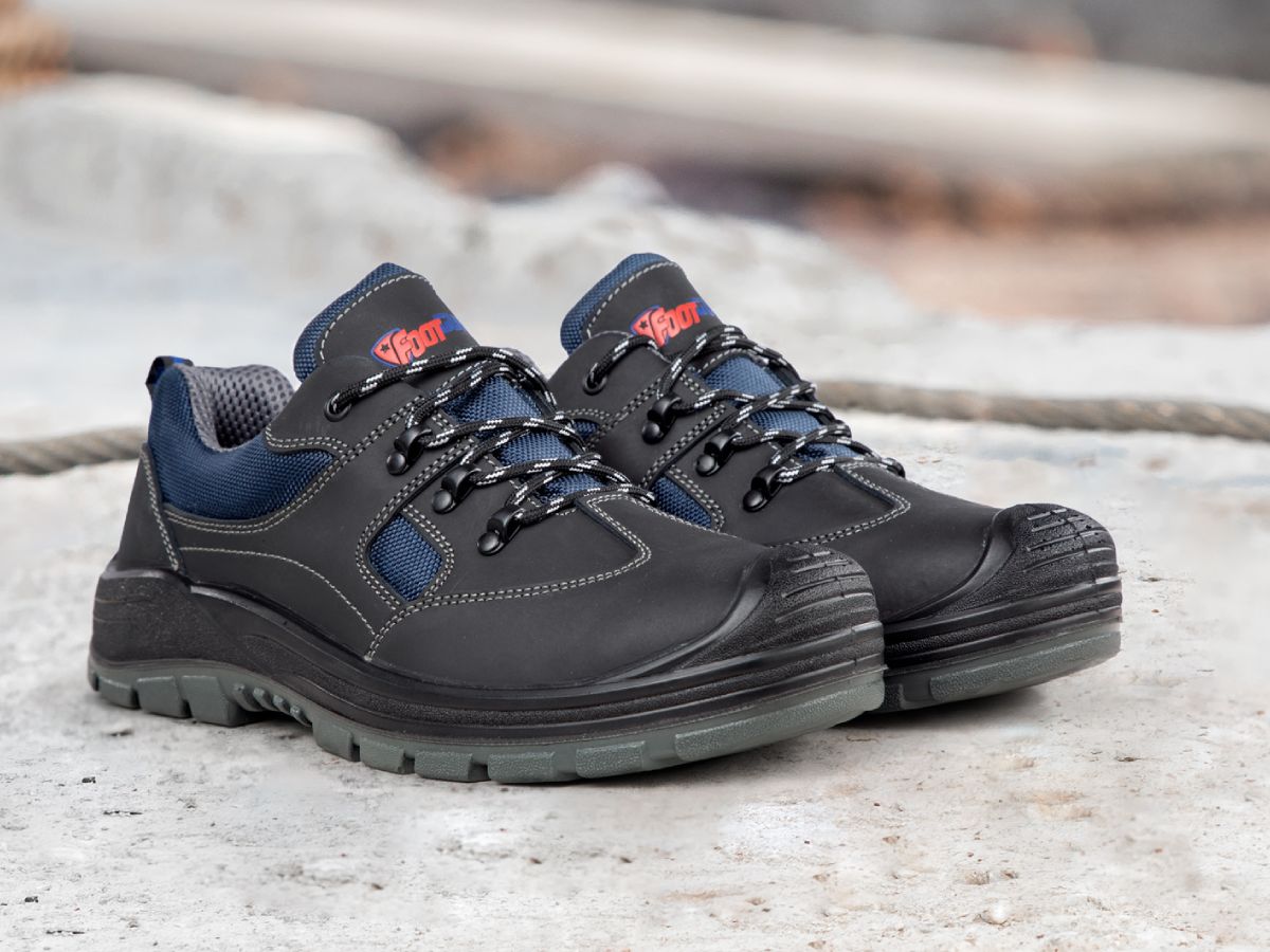 Sicherheitsschuh "Safe" von Footguard in Schwarz mit blauem Mesh-Einsätzen, stehend auf hellem Betonboden.