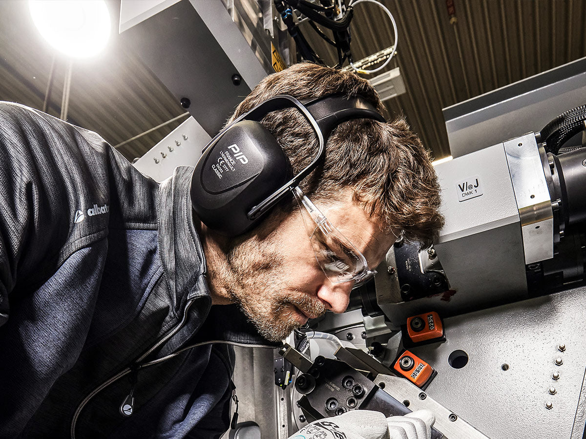 Arbeiter mit Gehörschutz von PIP und Schutzbrille an einer Maschine - optimaler Lärmschutz in der industriellen Fertigung.